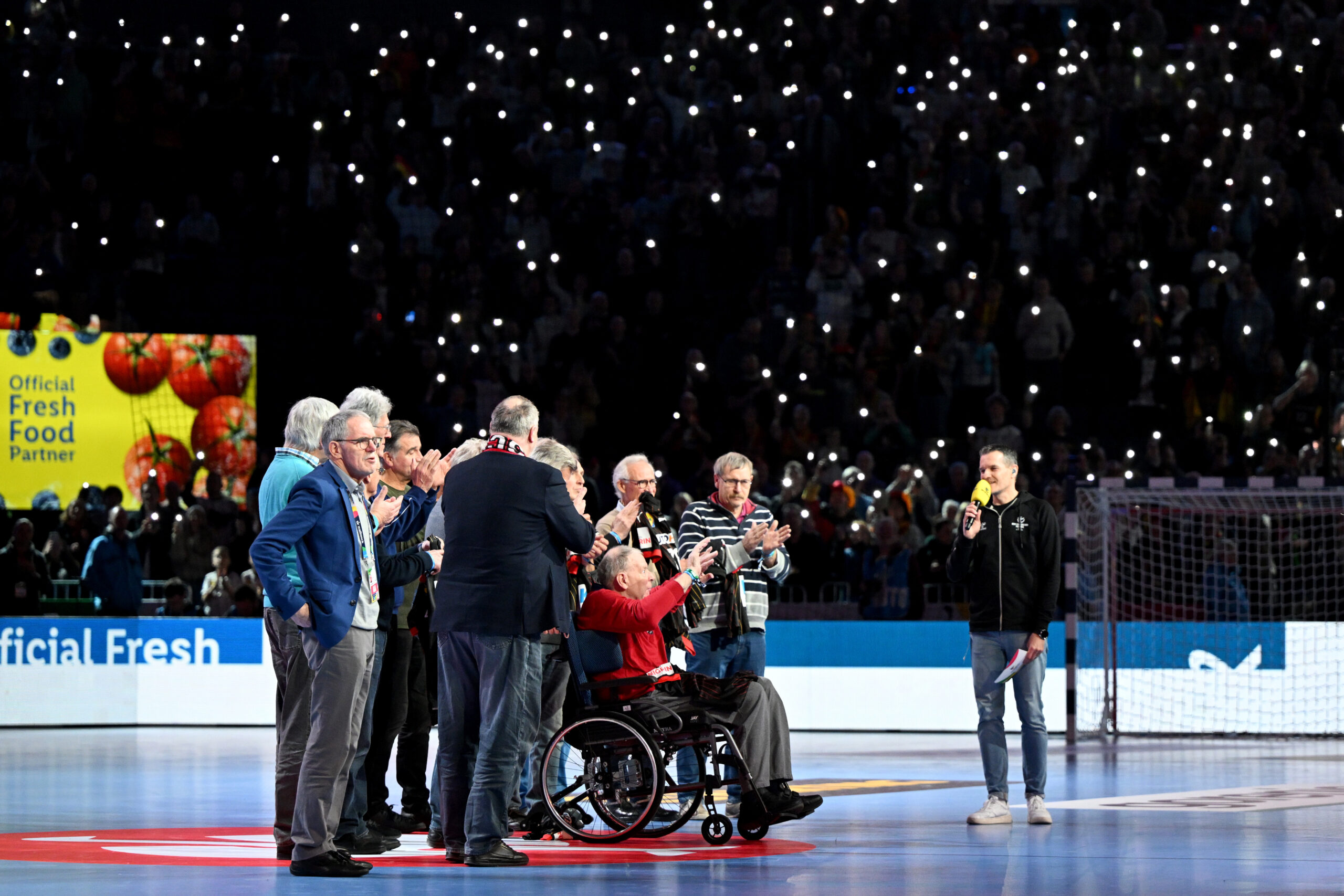 Joachim Deckarm im Rollstuhl in der Mitte der Lanxess-Arena während für ihn gesungen wird