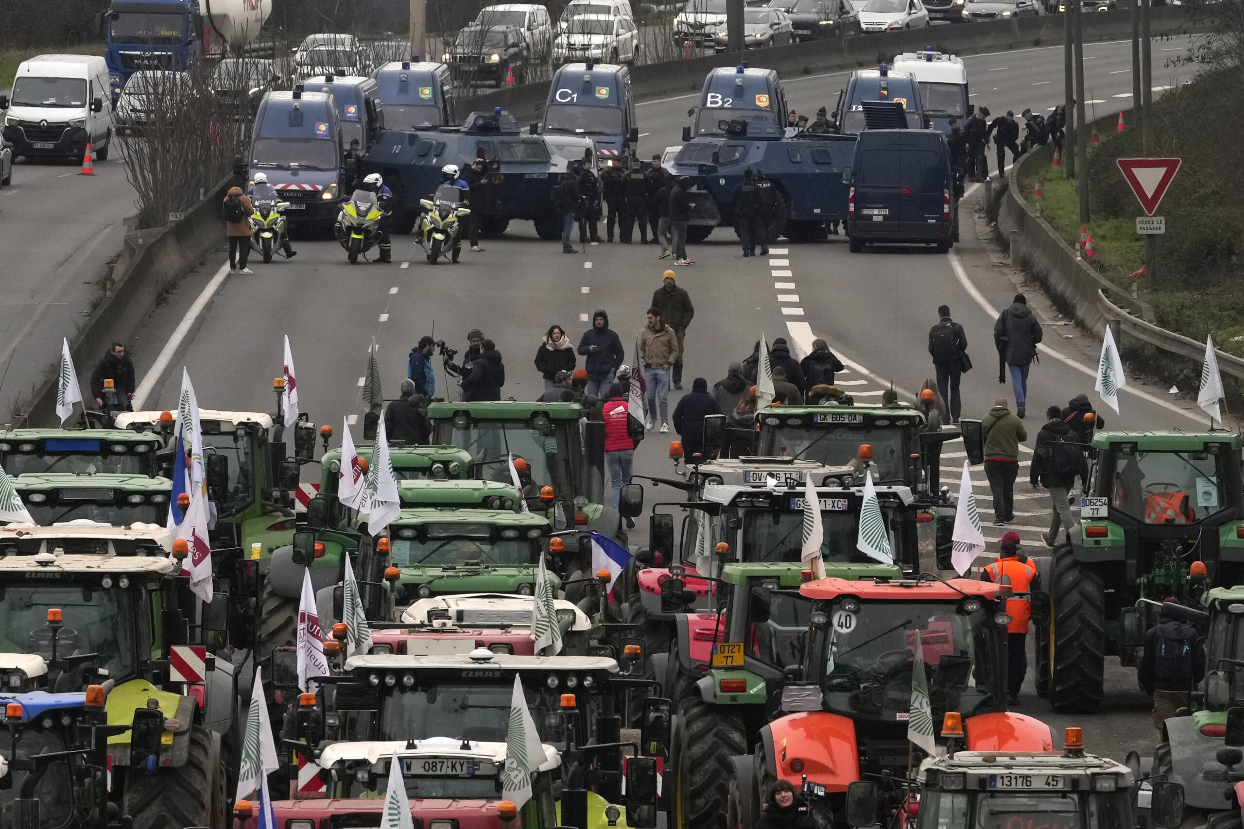 Landwirte und Traktoren stehen Militärfahrzeugen auf einer Autobahn gegenüber.