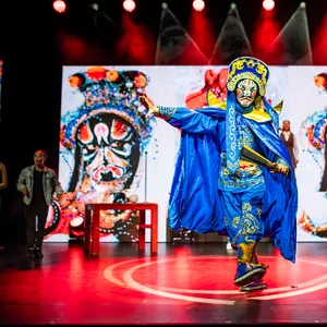 Tänzer in chinesischer Tracht, im Hintergrund auf der Bühne stehen Darstellerinnen und Darsteller