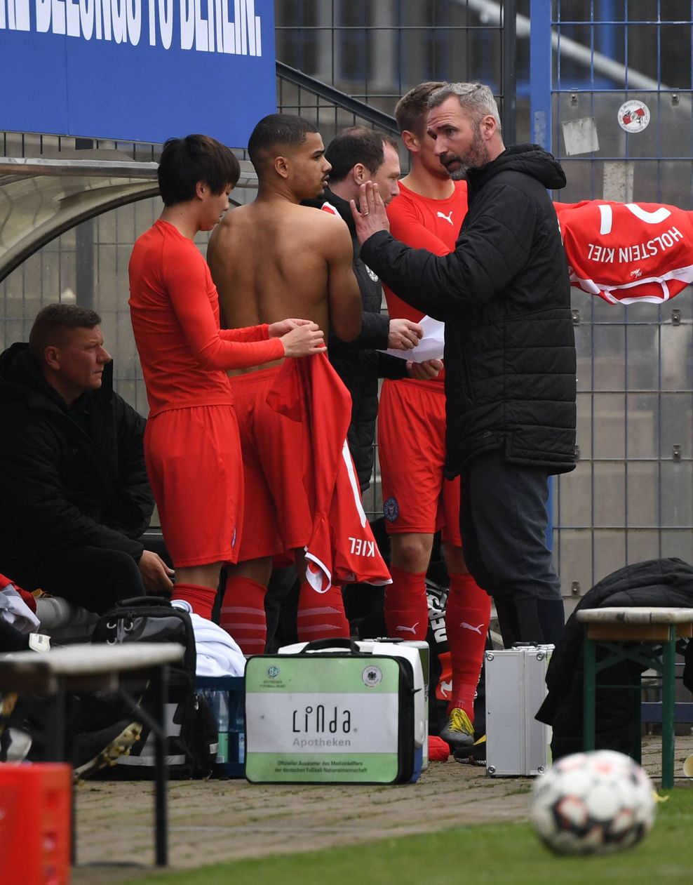 Tim Walter gibt Massaya Okugawa zu seiner Zeit als Trainer bei Holstein Kiel an der Auswechselbank Anweisungen