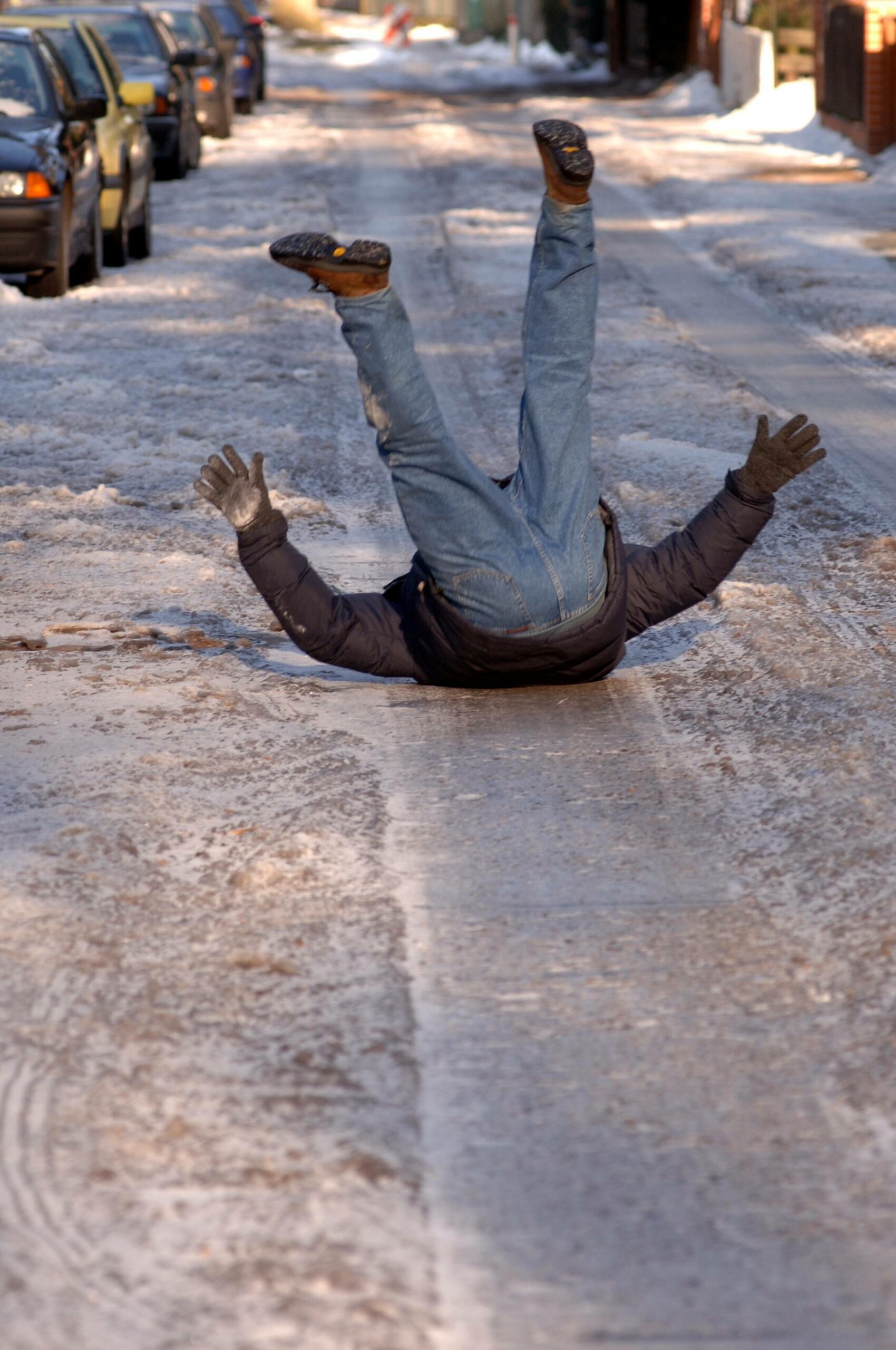 Ein Mann fällt auf einem glatten Gehweg.