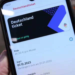 Ein Mann hält auf einem Bahnsteig sein Smartphone in der Hand, auf dem ein Deutschland-Ticket in der App des Hamburger Verkehrsverbundes ist. (Archivbild)