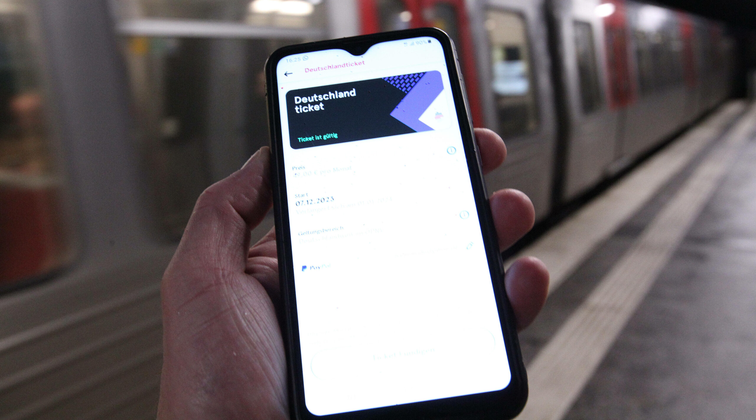 Ein Mann hält auf einem Bahnsteig sein Smartphone in der Hand, auf dem ein Deutschland-Ticket in der App des Hamburger Verkehrsverbundes ist. (Symbolbild)