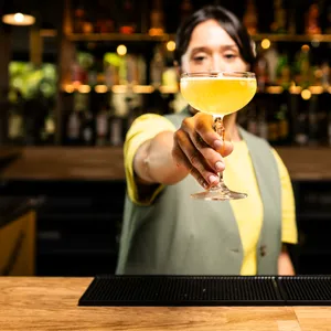 Eine Barkeeperin serviert einen Cocktail.