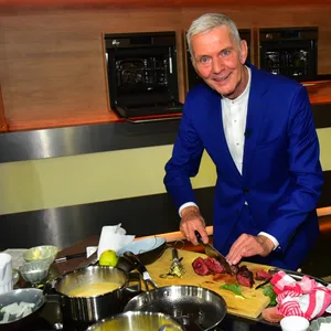 Volker Schimkus im blauen Anzug am Herd im TV-Küchenstudio