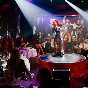 Spiegelzelt innen, kleine Bühne, an den Tischen drumherum sitzen Menschen, auf der Bühne singt eine Frau