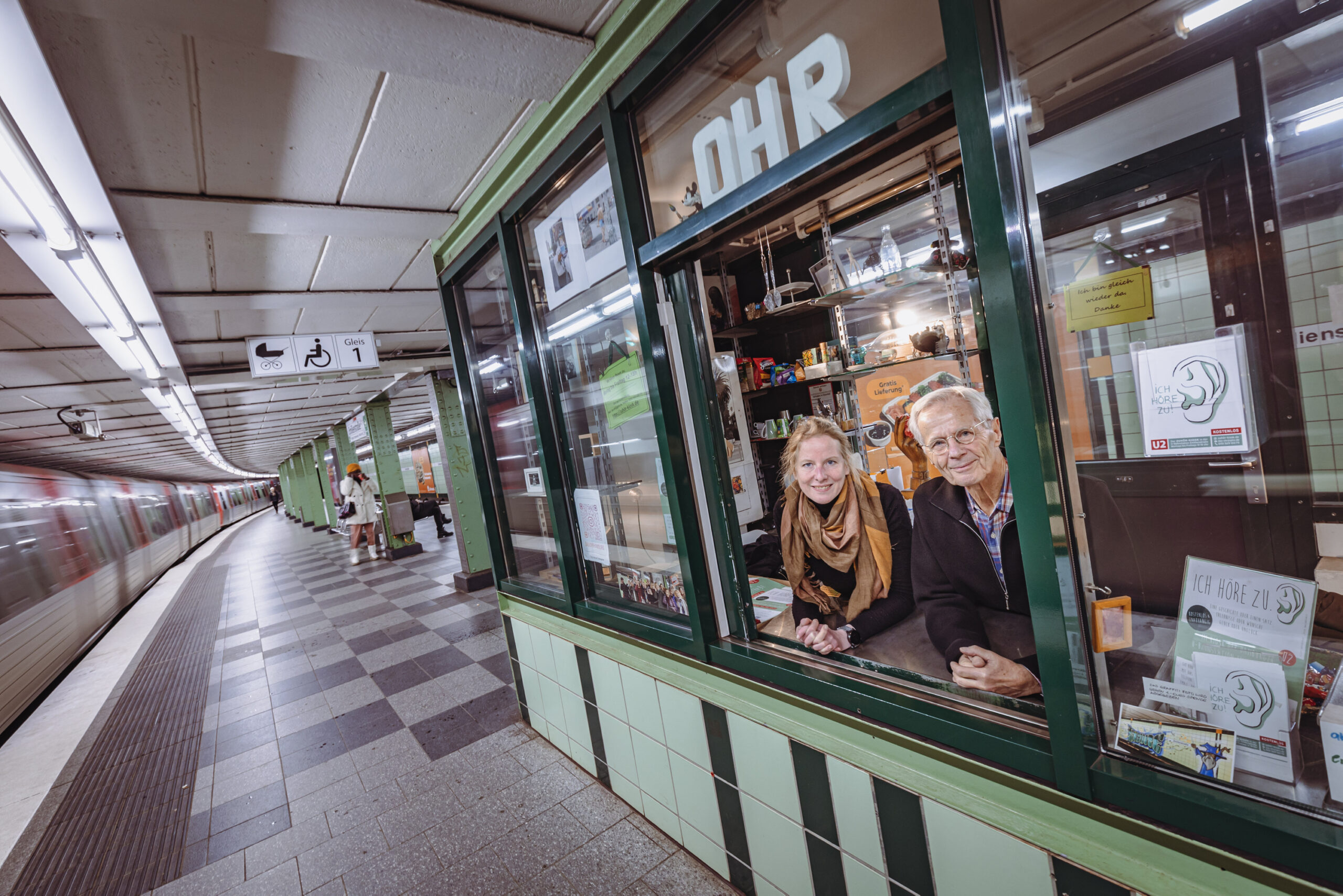 Die ehrenamtlichen Zuhörer Katharina McLean (l.) und Christoph Busch stehen am Fenster des Kiosk.