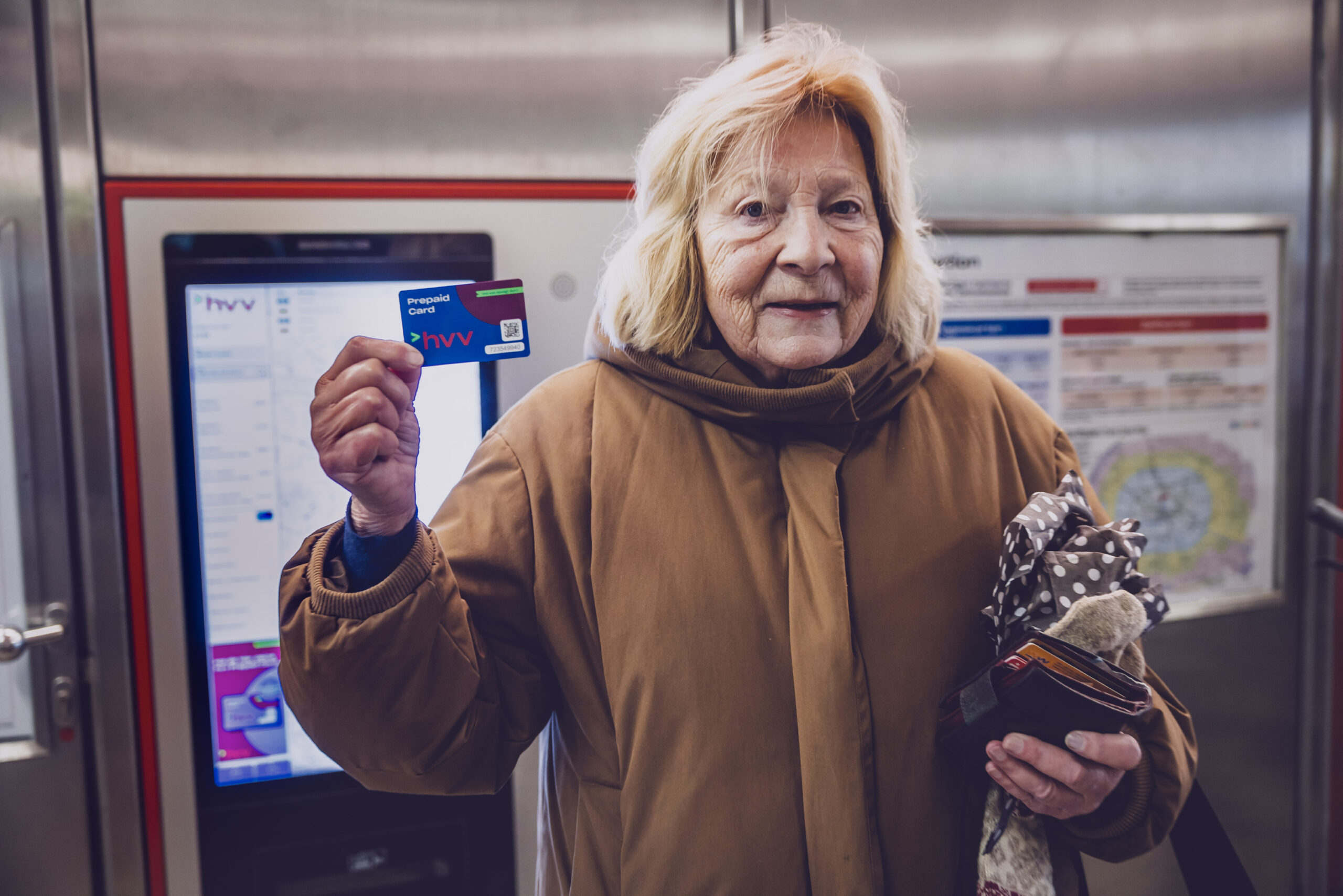 Anne K. vor einem Kartenautomaten des HVV. Sie hält eine Prepaid-Karte hoch.