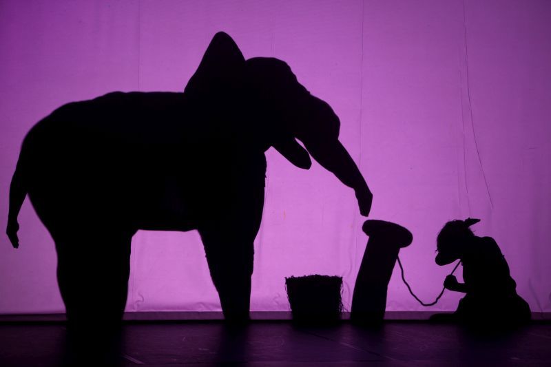 Links der Elefant, rechts kniet das Mädchen auf dem Boden