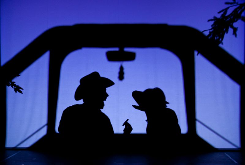 Schatten eines Mannes mit Cowboyhut und des Hundemädchens in einem angedeuteten Auto