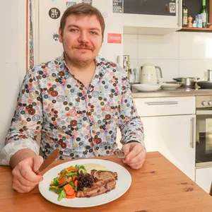Erwin Hitzler sitzt in seiner WG-Küche und isst sein Schwein