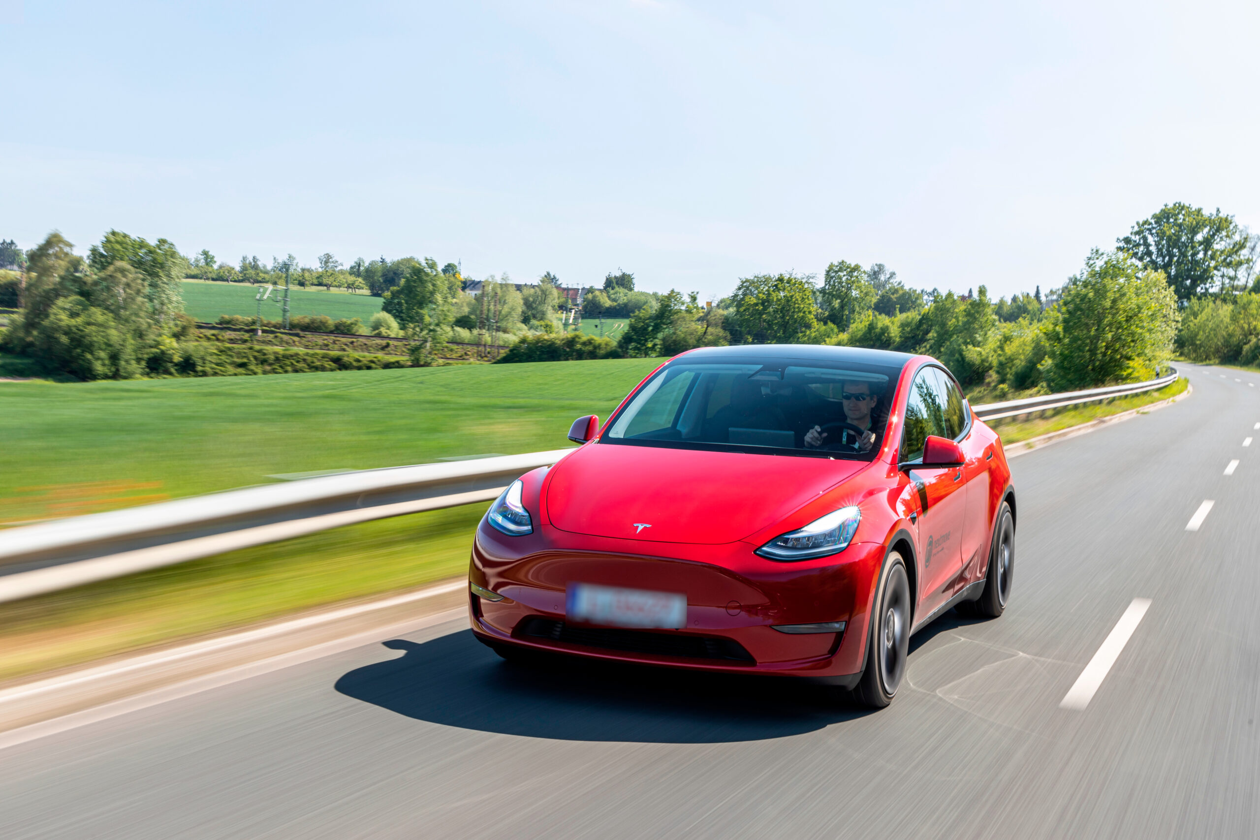 Ein roter Tesla fährt schnell auf einer Straße