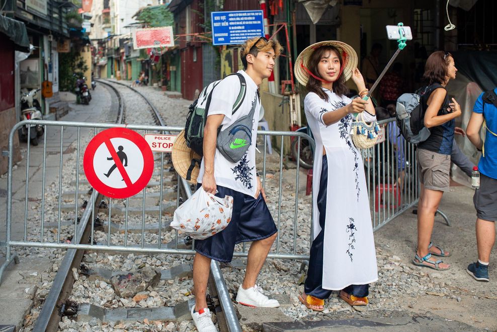 Zwei Touristen machen Selfies vor der abgesperrten „Train Street“ in Hanoi.