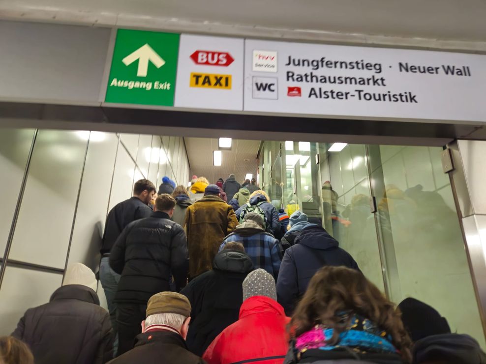 Viele Menschen gehen eine Treppe in einem Bahnhof in Hamburg hoch.