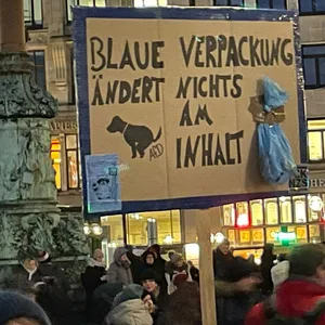 Die Botschaft an die AfD ist klar: „Blaue Verpackung ändert nichts am Inhalt.“ Auf dem Schild ist auch ein Hund zu sehen, der sein Geschäft verrichtet.