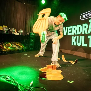 Mann auf der Bühne zertrümmert eine Akustikgitarre