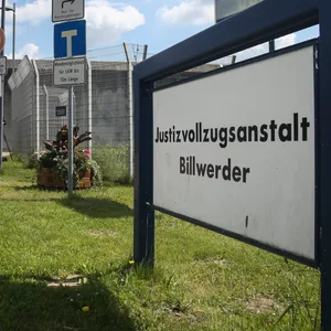 Hohe Mauer mit Schild: „Justizvollzugsanstalt Billwerder“