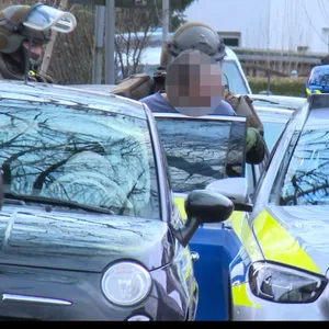 Spezialkräfte setzen den 71-Jährigen in einen Streifenwagen.