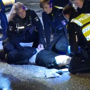 Beamte versorgen den mutmaßlichen Angreifer, der laut Polizei erst durch einen Hundebiss gestoppt werden konnte.