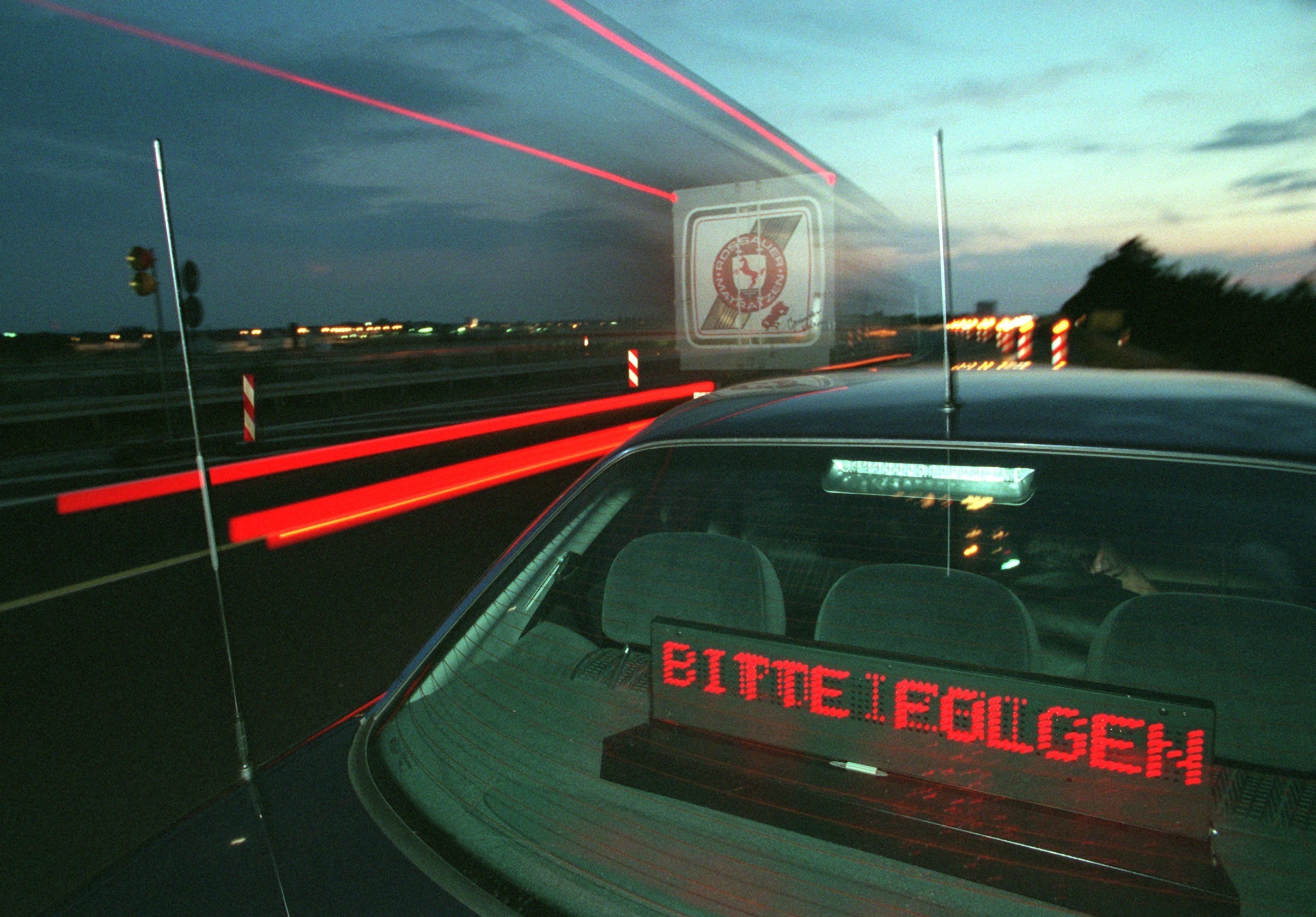 Ein Polizeiwagen, an der Heckscheibe leuchtet der Schriftzug "Bitte folgen" auf