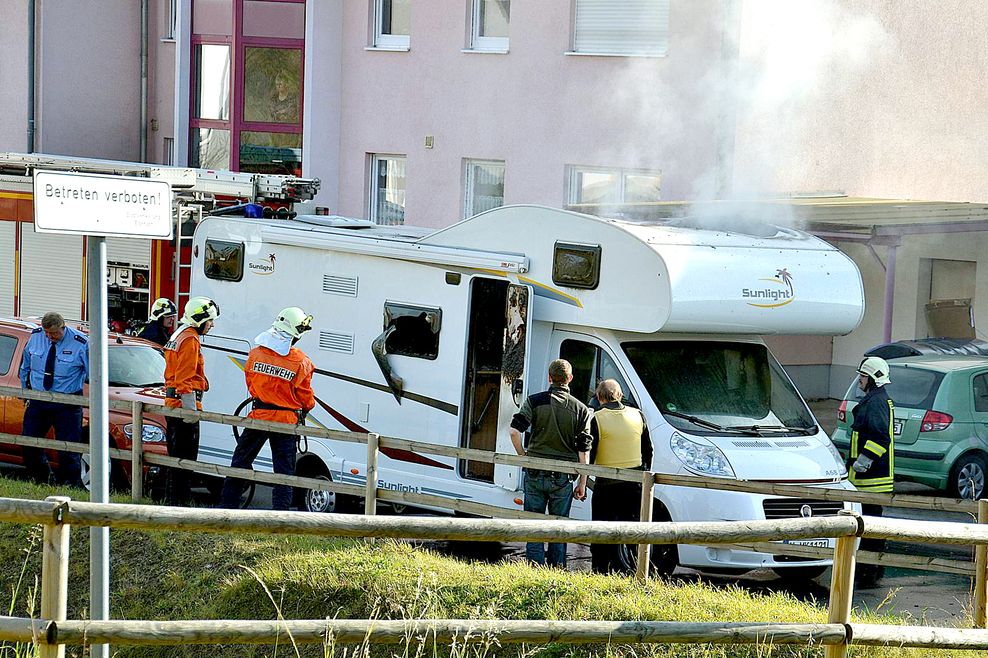 Eisenach am 4. November 2011: Feuerwehrleute und Polizisten stehen am vor einem qualmenden Wohnmobil, in dem zwei Leichen entdeckt wurden. Kurz zuvor hatten sich die beiden NSU-Terroristen erschossen.