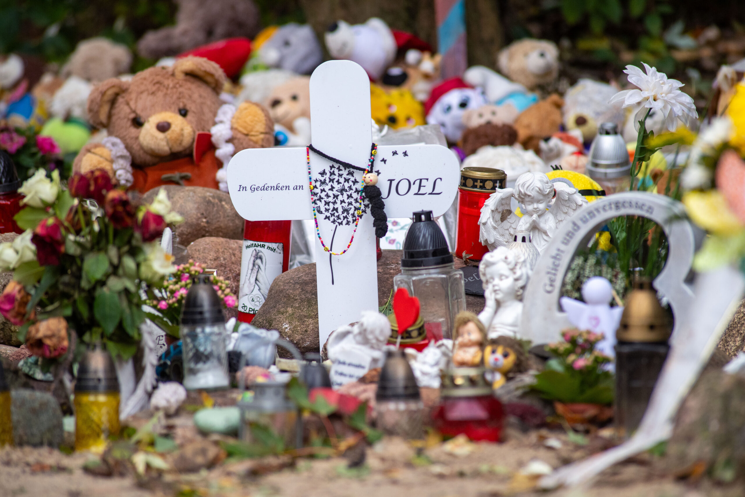 Nahe der Stelle in Pragsdorf, wo ein Sechsjähriger am 14.09.2023 mit Stichverletzungen gefunden wurde, an denen er später verstarb, sind unter anderem Kreuze, Plüschtiere und Blumen abgelegt worden.