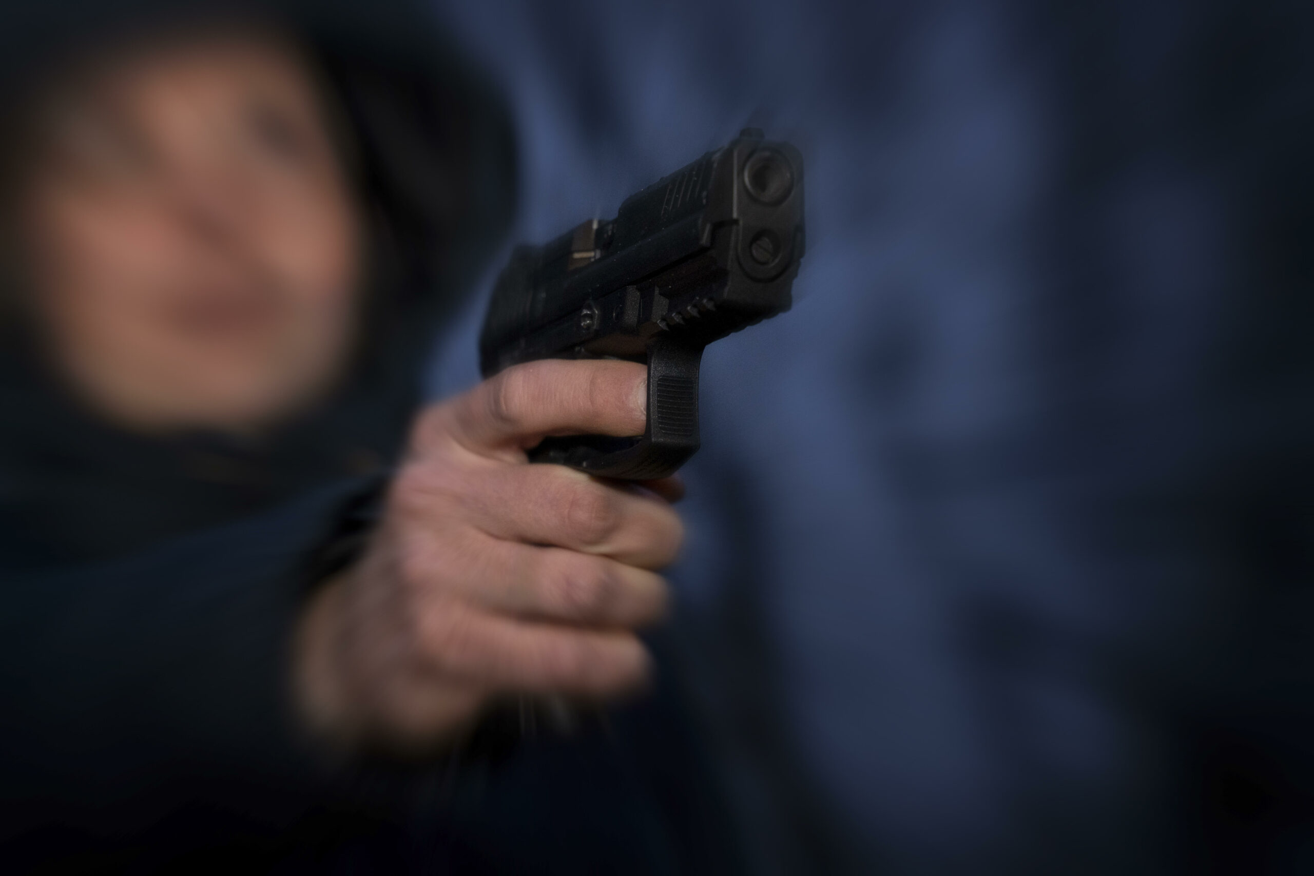 Ein Mensch hält eine Waffe, das Bild ist unscharf (Symbolfoto).