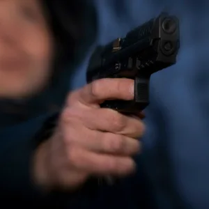 Ein Mensch hält eine Waffe, das Bild ist unscharf (Symbolfoto).