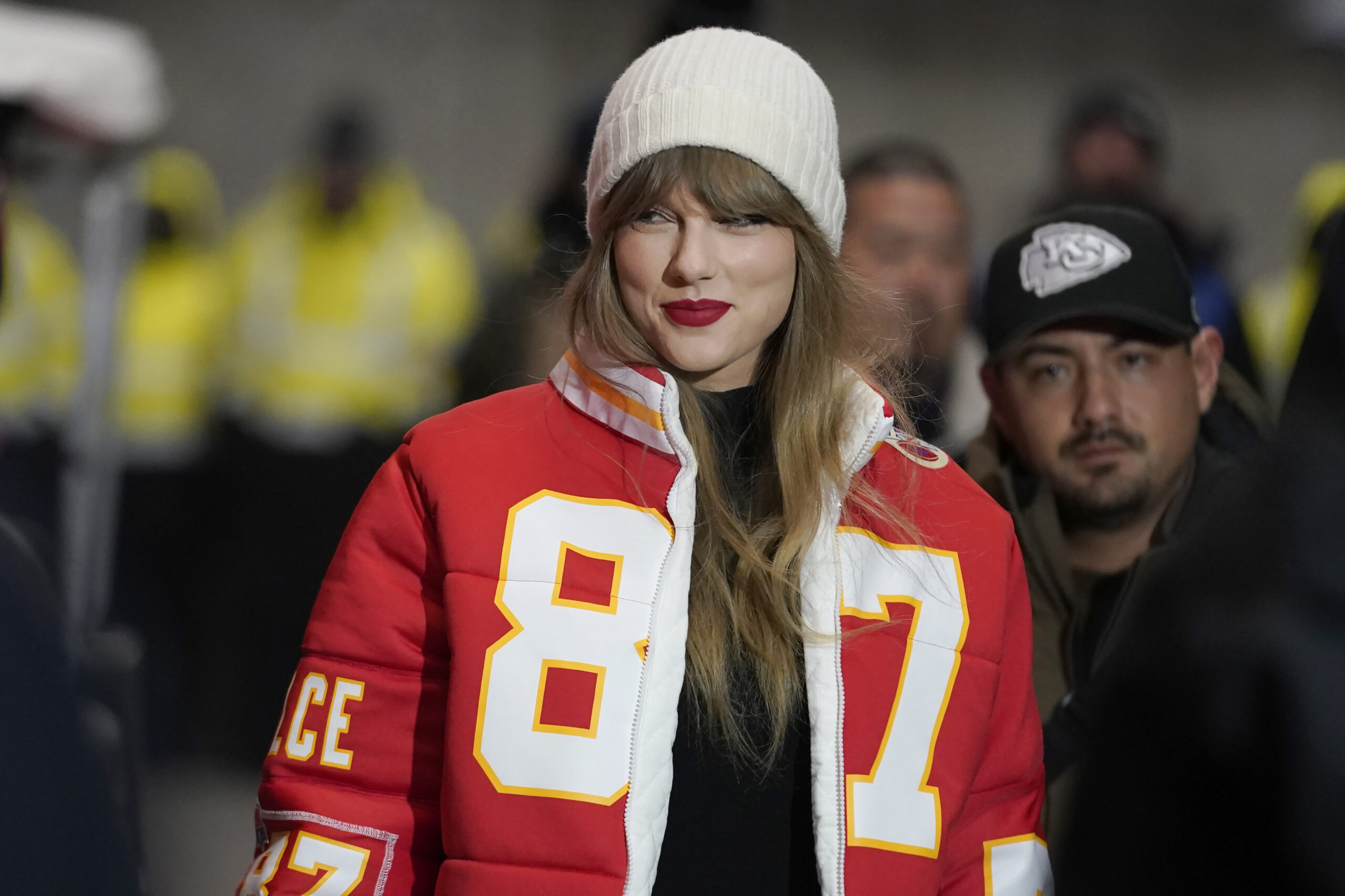 Taylor Swift trägt eine rote Jacke mit Travis Kelces Nummer und Namen drauf - sie lächelt