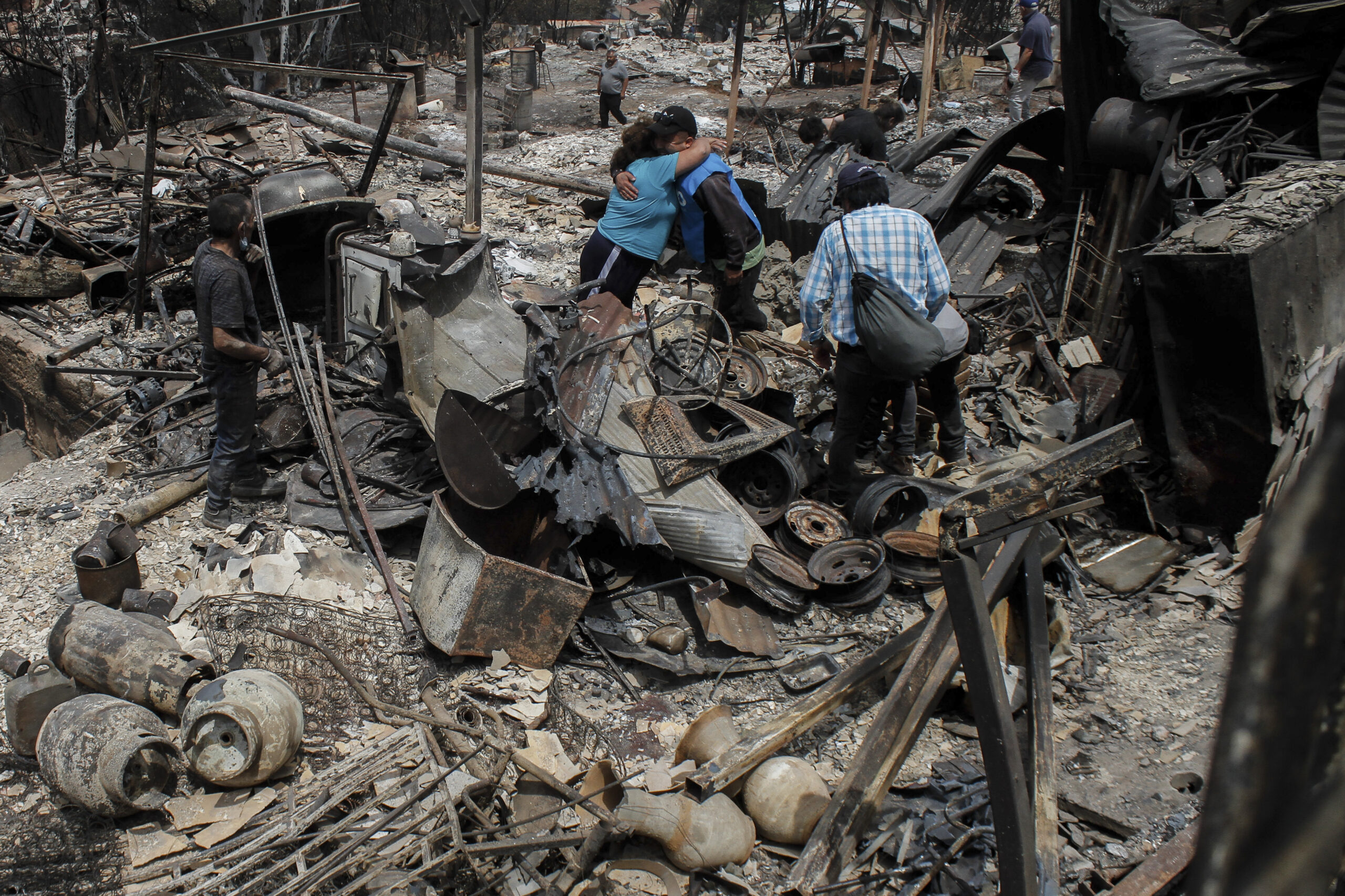 Zwei Anwohner umarmen sich auf den Überresten der Häuser nach dem Brand
