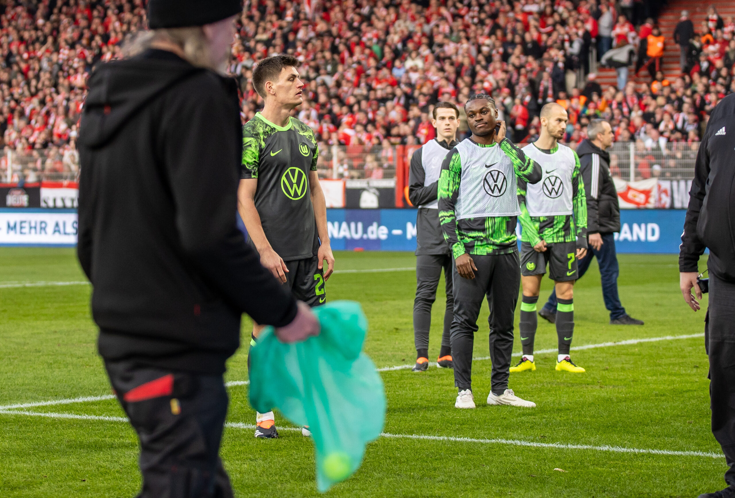 Spieler des VFL-Wolfsburg versuchen ihre Fans davon abzuhalten, Gegenstände auf das Spielfeld zu werfen.
