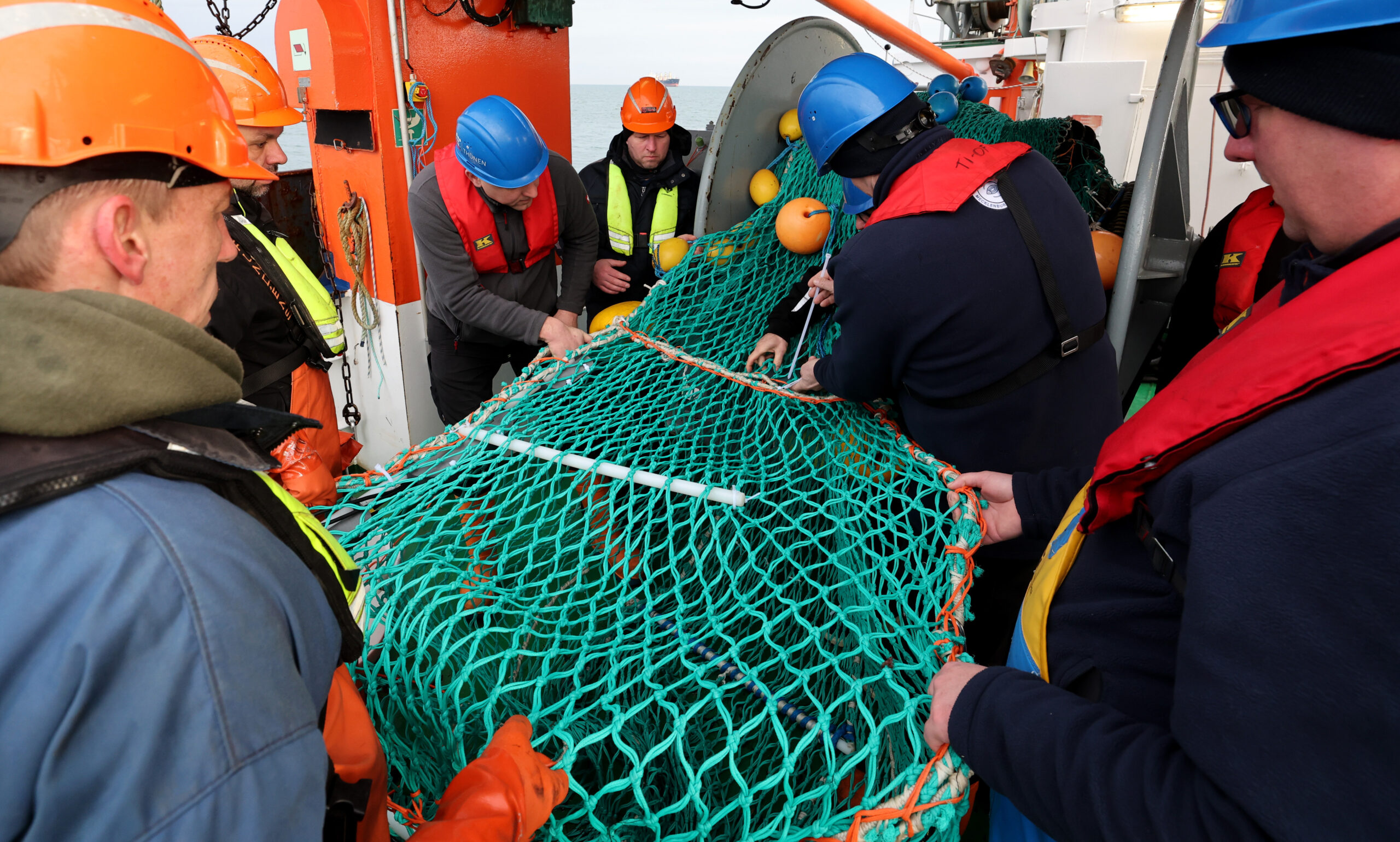 Besatzungsmitglieder und Fischer bereiten ein Schleppnetz für den nächsten Einsatz mit Kameras vor