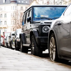 Ein SUV steht geparkt zwischen kleineren Fahrzeugen auf einem Parkstreifen.