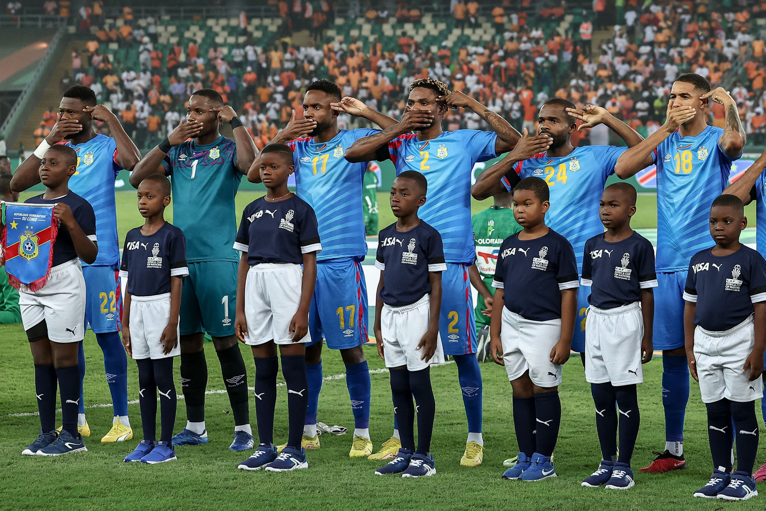 Die Nationalspieler der Demokratischen Republik Kongo halten sich ihre Mander zu und legen zwei Finger an den Kopf während ihrer Hymne.