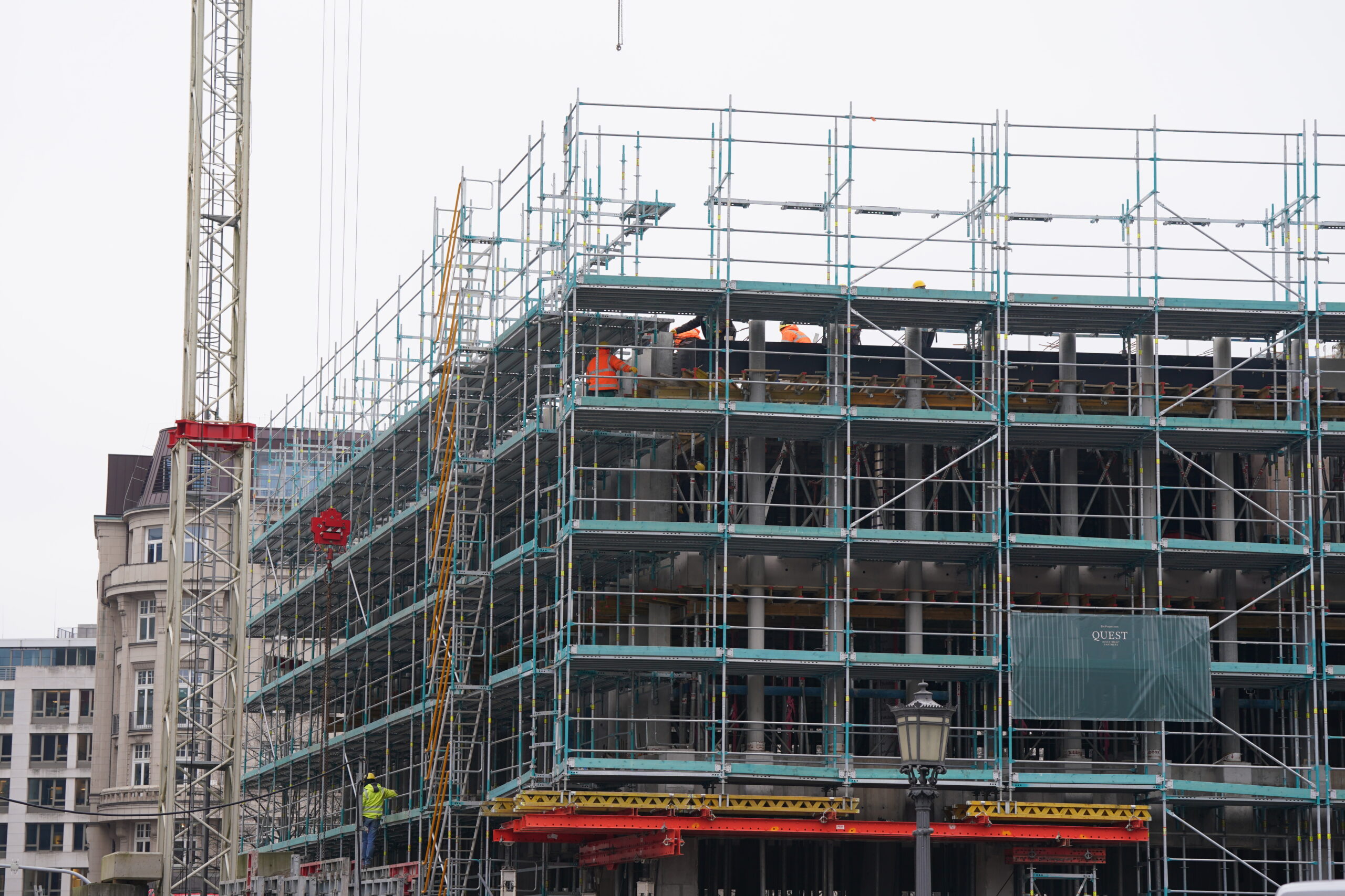 Bauarbeiter stehen auf einem Baugerüst an einer Baustelle in der Innenstadt.