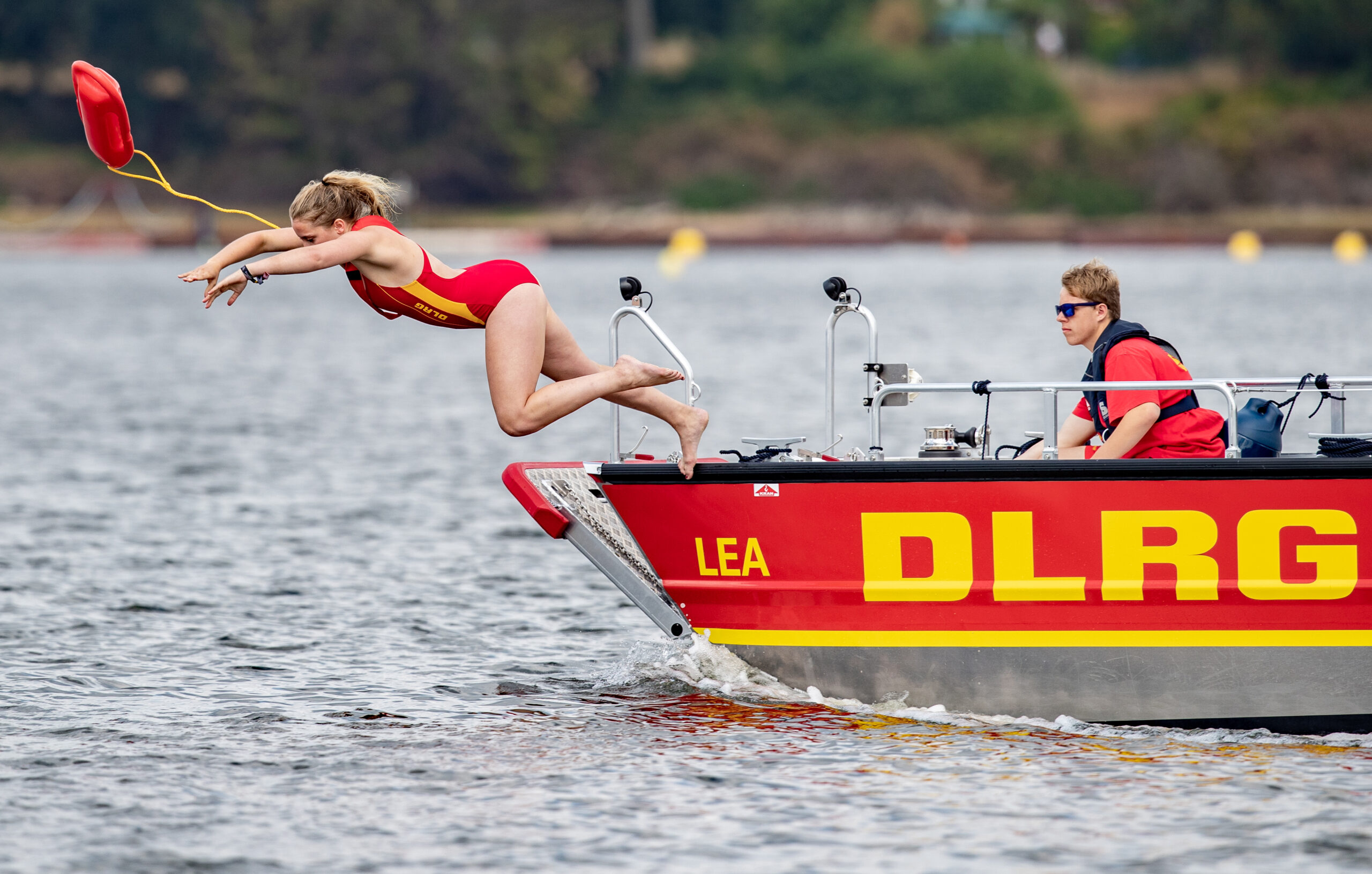 Eine Rettungsschwimmerin der DLRG springt während einer Übung in einen See.