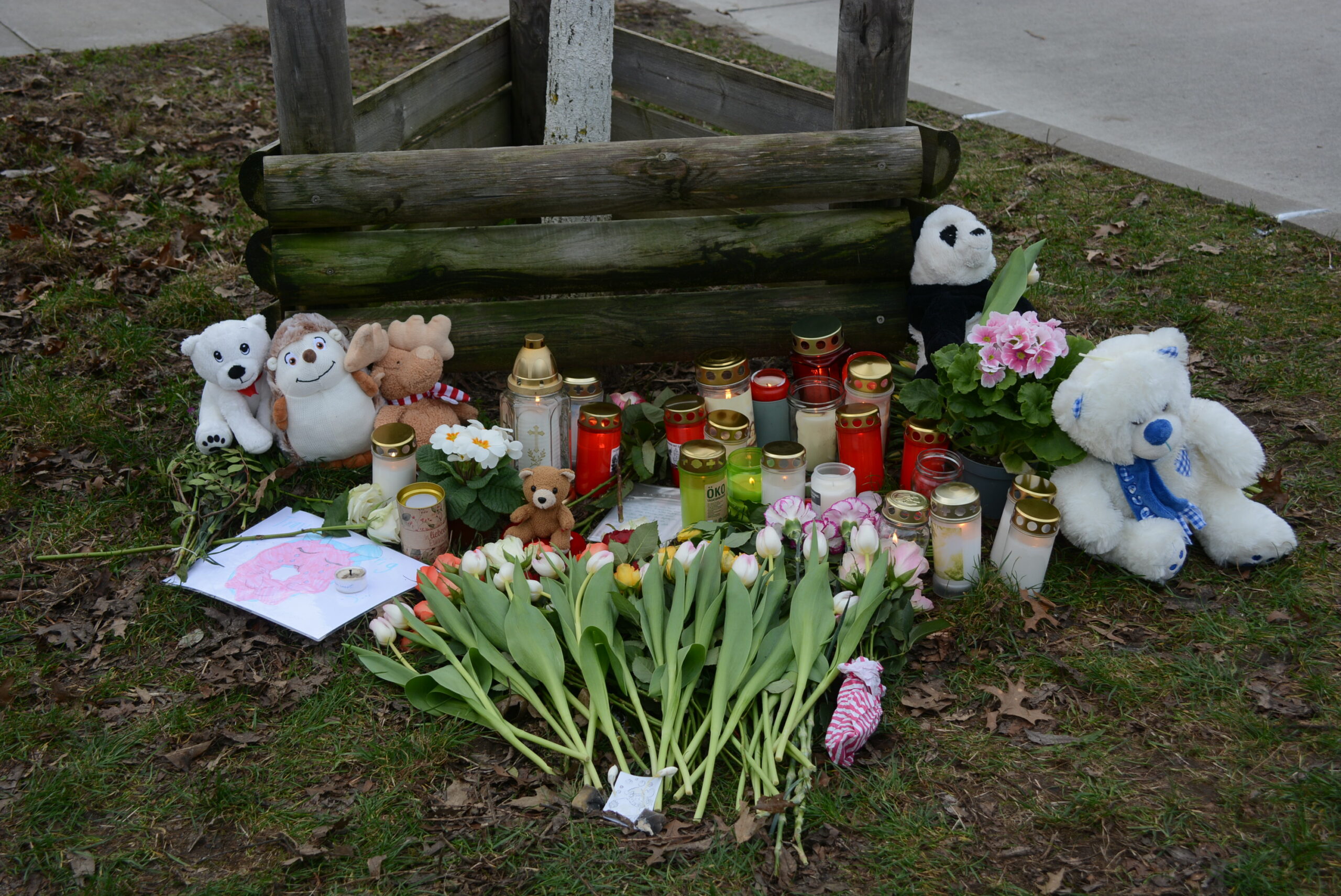 Trauernde haben Blumen, Kerzen und Kuscheltiere an der Bushaltestelle abgelegt, an der der Junge überfahren worden war.