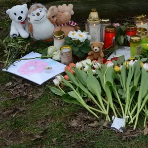 Trauernde haben Blumen, Kerzen und Kuscheltiere an der Bushaltestelle abgelegt, an der der Junge überfahren worden war.