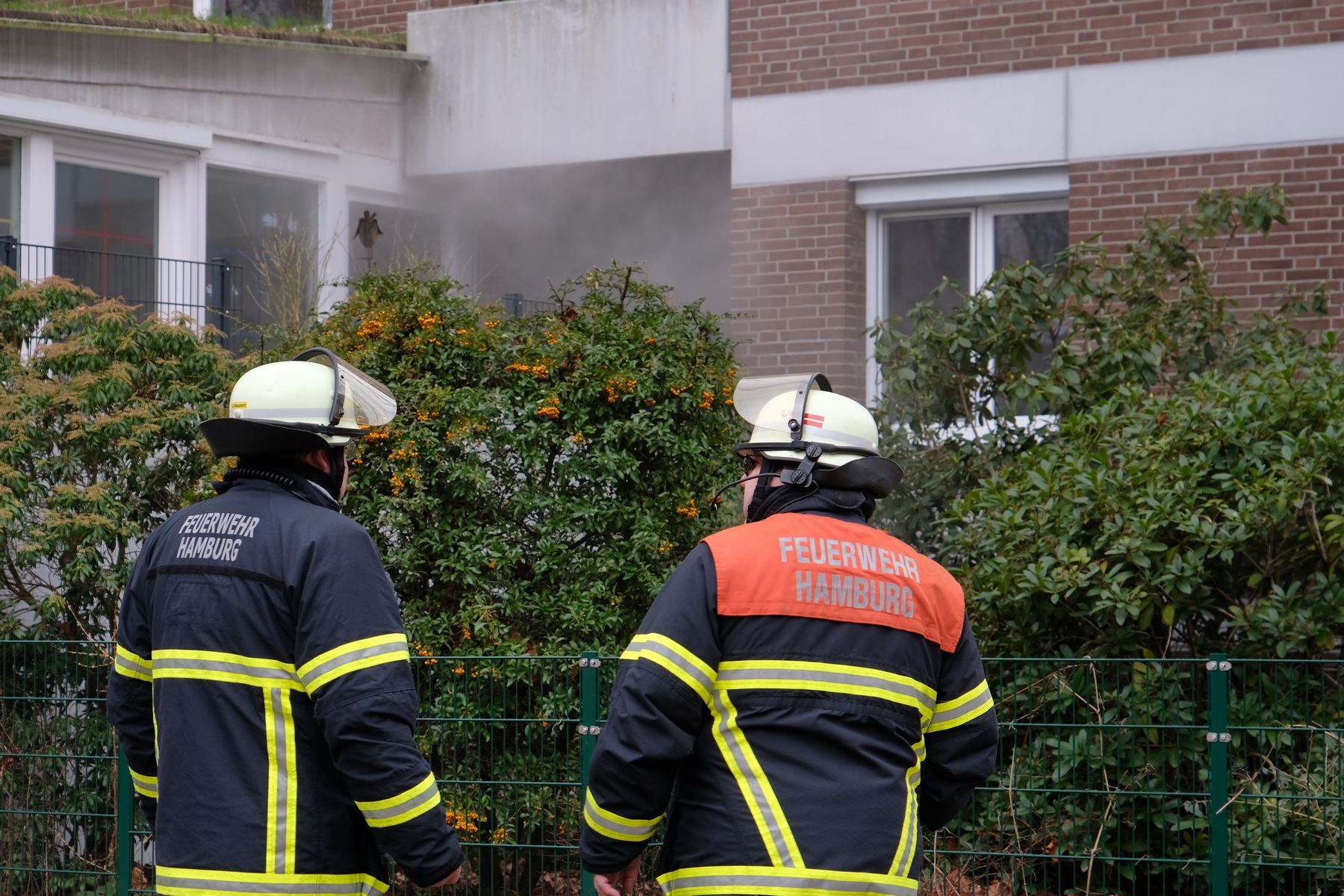 Feuerwehrmänner vor brennendem Mehrfamilienhaus