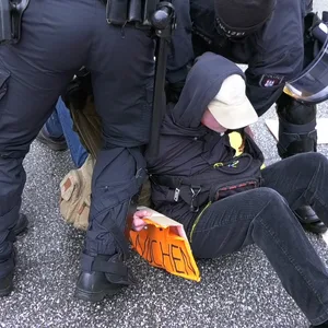 Zwei Demonstrierende wurden von der Polizei mit Gewalt von der Straße entfernt.