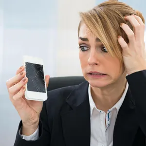 Eine Frau hält ihr kaputtes Smartphone in der Hand.