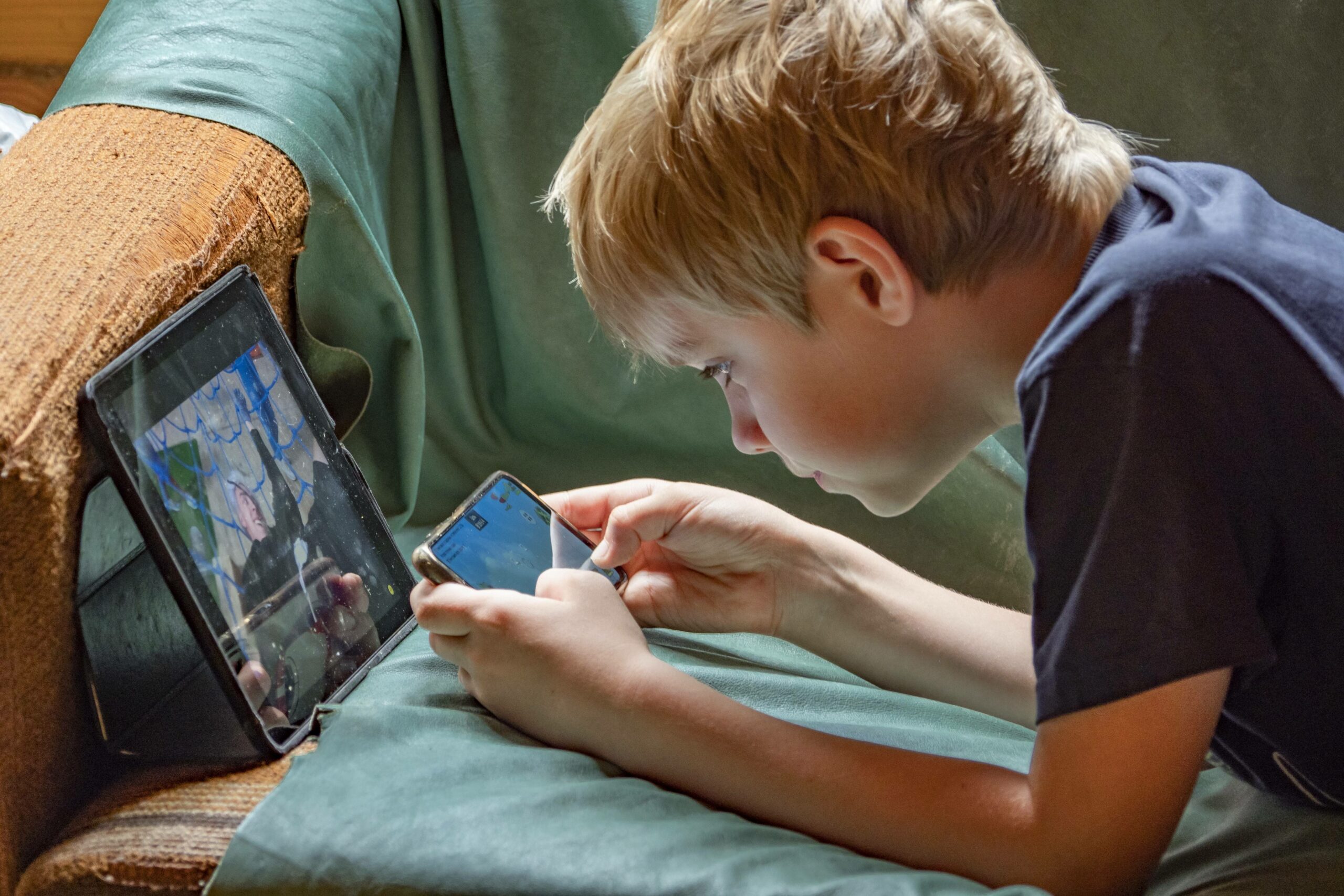 Ein Junge beschäftigt sich mit einem Tablet und einem Smartphone. (Symbolbild)
