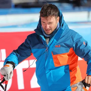 Felix Neureuther in Winterjacke und mit Ski-Stöcken in den Händen.
