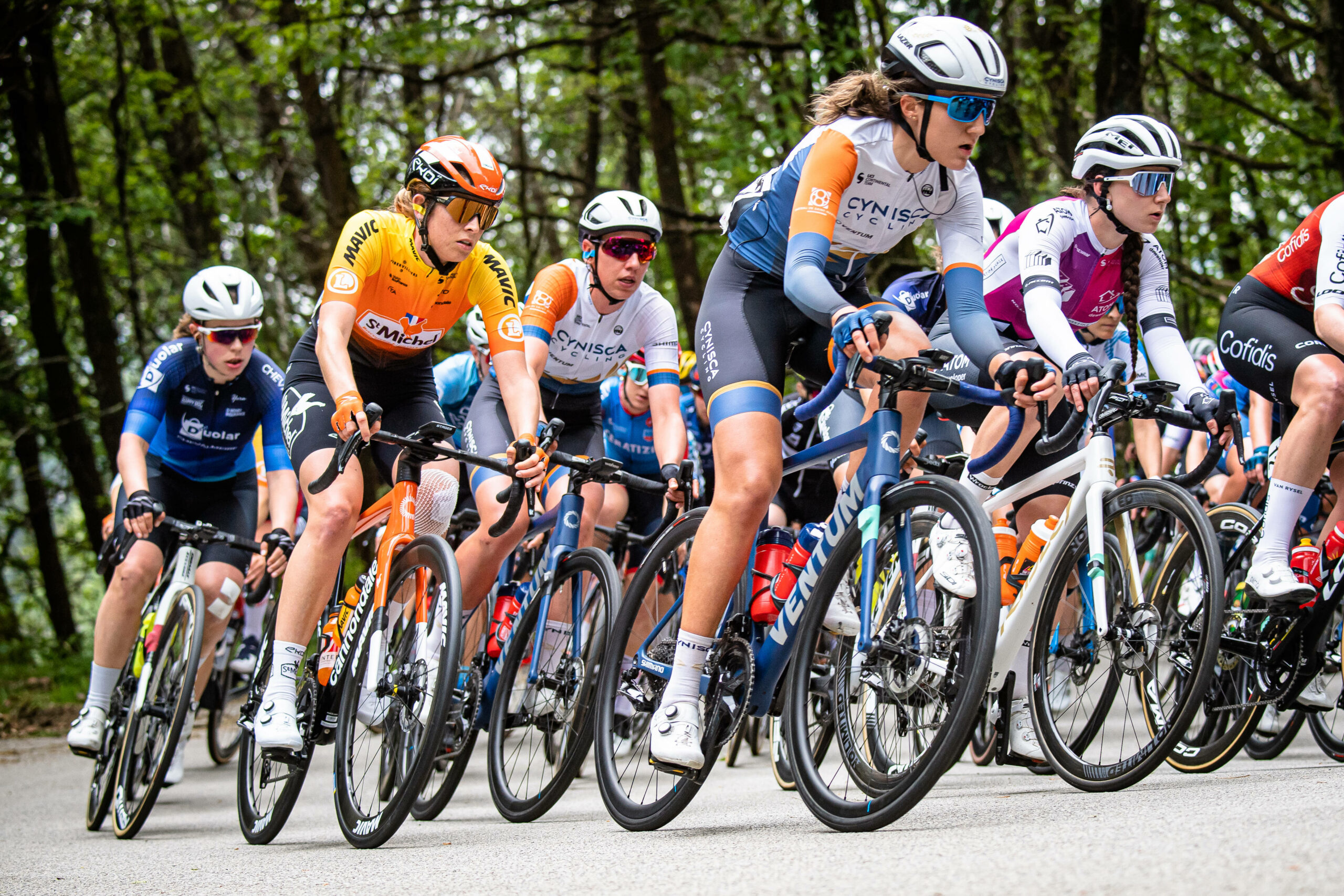 Eine Rennradfahrerin des Teams Cynisca Cycling bei einem Wettkampf mit anderen Teilnehmenden.