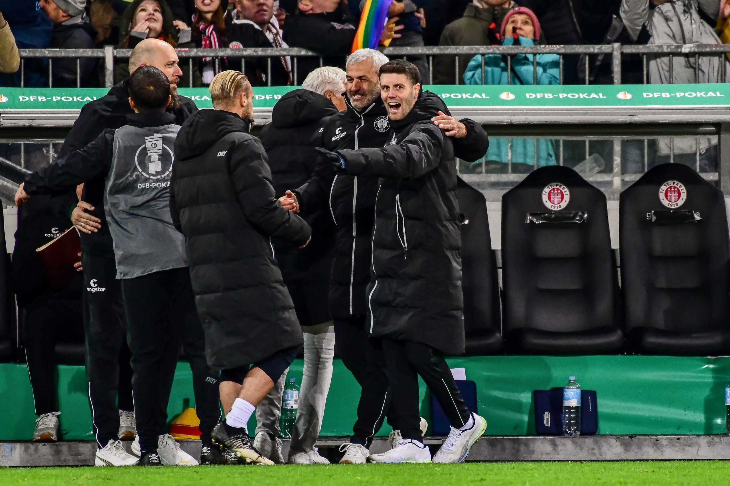 Fabian Hürzeler feiert mit seinem Trainer-Team vor der Bank.