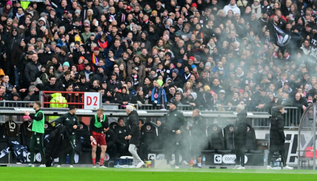 St. Pauli-Bank in Aufruhr, vom Spielfeld steigt Rauch auf