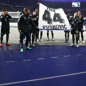 Die Spieler des HSV halten ein Banner mit der Aufschrift „Free Vuskovic“ Richtung eigener Fankurve hoch.