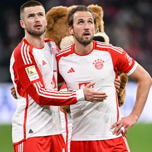 Eric Dier und Harry Kane stehen sich einhakend vor der Fankurve des FC Bayern.