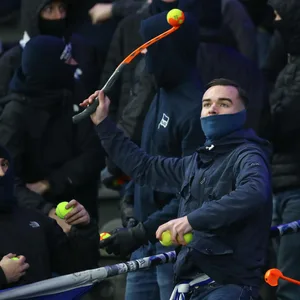 Ein Hertha-Ultra schleudert Tennisbälle auf den Platz.