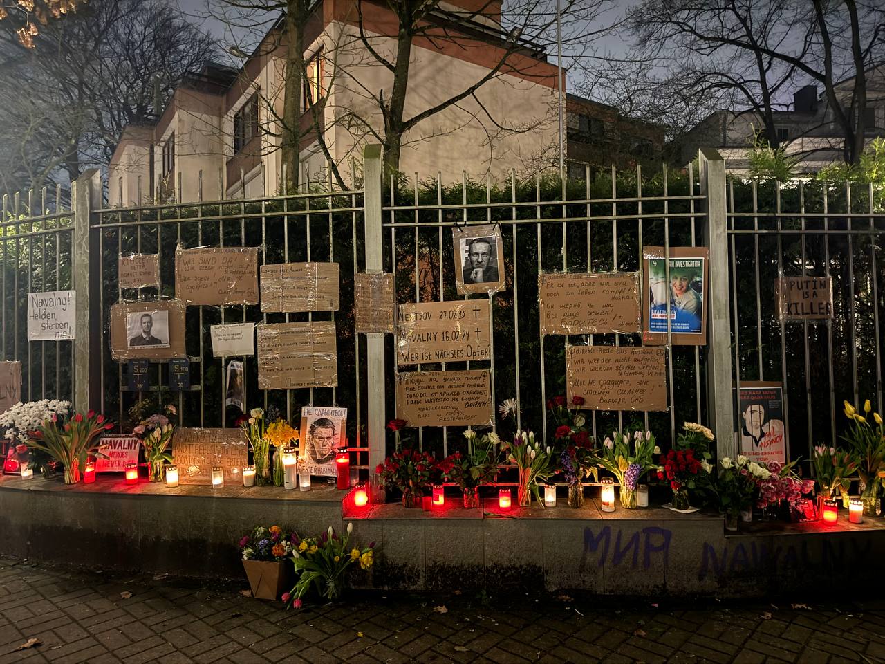 Trauer um Nawalny vor ehemaligem russischen Konsulat, am Zaun hängen Fotografien von Navalny, Briefe, es sind Blumen und Kerzen abgelegt